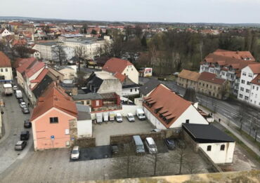 Das Foto zeigt leerstehende Häuser am Schlossplatz. Dazwischen parken Autos.