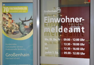 Das Foto zeigt eine Glastüre. Auf dieser stehen das Wort "Einwohnermeldeamt" und Öffnungszeiten.