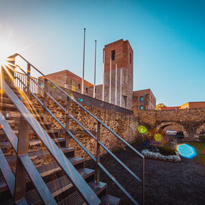 Das Foto zeigt eine stimmungsvolle Ansicht des Bergfriedes am Kulturschloss im Abendsonnenschein.