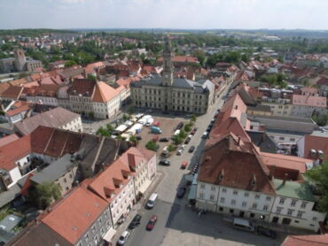 Das Foto zeigt einen Blick auf das Rathaus und den Hauptmarkt. Man sieht die Häuser der Stadt und die Autos, die auf den Straßen fahren.