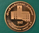 Man sieht eine bronzefarbene Münze. Darauf erkennt man das Kulturschloss.