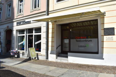 Das Foto zeigt ein Ladengeschäft am Hauptmarkt. Die Fenster sind mit einer Sichtfolie. Auf der Folie stehen die Texte "Corona-Testzentrum" und "Große Kreisstadt Großenhain".