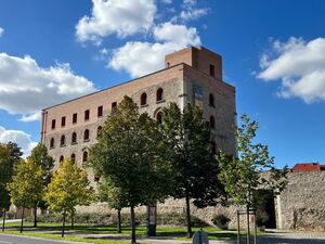 Das Foto zeigt das Kulturschloss Großenhain, ein rechteckiges, dreistöckiges massives Gebäude aus Stein. Oberhallb der dritten Etage sieht man den Bergfried, einen Turm.