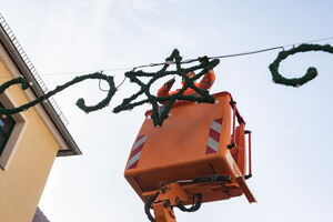 Das Foto zeigt einen Mitarbeiter des Bauhofes. Er steht in einem Hubsteiger. Von hier aus arbeitet er an einer Weihnachtsbeleuchtung in Sternenform.