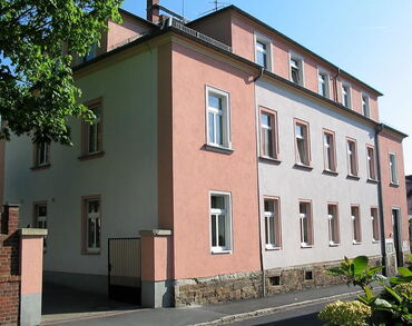 Das Foto zeigt ein zweistöckiges, rosafarbenes Gebäude.