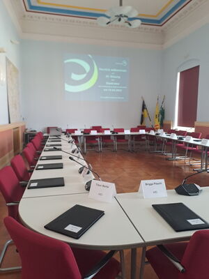 Das Foto zeigt den Sitzungssaal des Rathauses. Man sieht Stühle und Tische. Auf den Tischen liege Mappen und man erkennt Namensschilder.