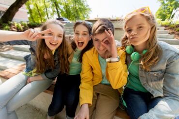 Das Foto zeigt vier Jugendliche, drei Mädchen und einen Jungen, die albern und dabei in die Kamera lachen.